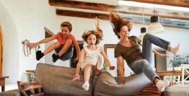Mutter hüpft mit Kindern übers Sofa